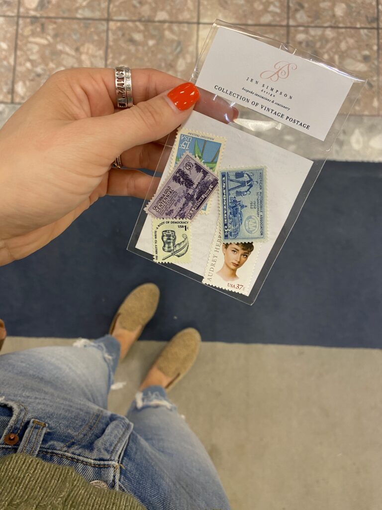 Amanda DeWoody of Poised Avenue holding a collection of vintage stamps meant to custom stationery.